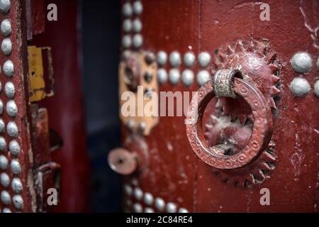 Marocco, Tetouan: Dettaglio del battente rosso circolare di una porta decorata con borchie d'argento nella medina, registrato come patrimonio dell'umanità dell'UNESCO Foto Stock