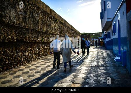 Marocco, Asilah: Località balneare sulla punta nord-occidentale della costa atlantica, a sud di Tangeri. Gruppo di uomini in Bournous che cammina lungo i bastioni di t Foto Stock