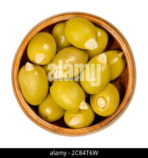 Olive verdi farcite di mandorle in ciotola di legno. Olive europee grandi, frutti di Olea europea, farcite a mano con mandorle croccanti sottaceto. Foto Stock