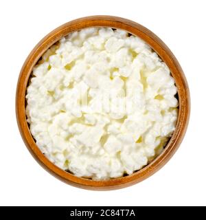 Ricotta il formaggio in una ciotola di legno. Prodotto fresco di cagliata di formaggio noto anche come caglidi e siero di latte, dal sapore delicato. Ai grani di cagliata viene aggiunta una crema. Foto Stock