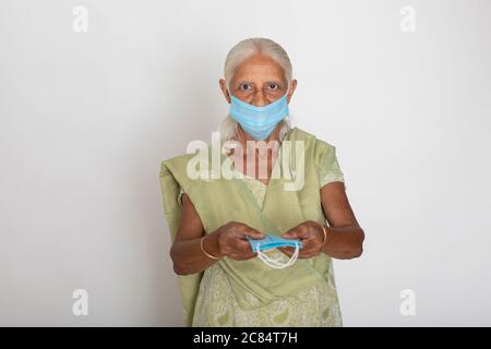 Donna indiana matura che indossa maschera di protezione Covid, nonna indiana mostra maschera di protezione del viso Foto Stock