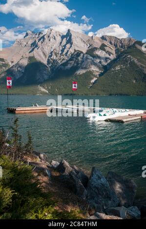 Bandiera canadese Maple Leaf e motoscafi sul lago Minnewanka, Banff, Alberta, Canada. Foto Stock