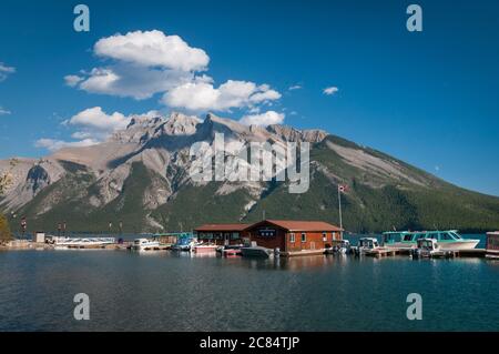 Bandiera canadese Maple Leaf e motoscafi sul lago Minnewanka, Banff, Alberta, Canada. Foto Stock