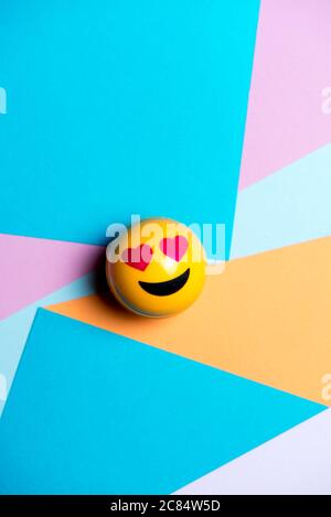 emoticon giallo sorridente con occhi cardiaci, struttura geometrica multicolore, concetto di social media Foto Stock