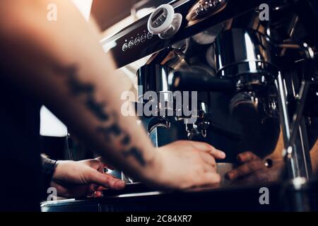 Un barista professionista trasforma i chicchi di caffè macinati in caffè spesso aromatico utilizzando macchine speciali Foto Stock