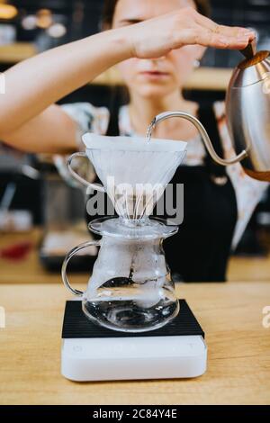 Preparazione del caffè con un filtro a forma di imbuto su un recipiente di vetro Foto Stock