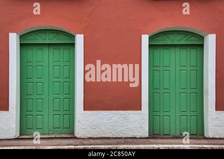 Un paio di porte verdi luminose in un muro dipinto di rosso e bianco su una strada in Alter do Chao, Para state, Brasile Foto Stock