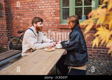 Giovane e bella coppia che riposa felice insieme bevendo caffè nella caffetteria di strada Foto Stock