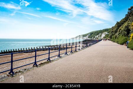 Eastbourne Promenade, East Sussex, Inghilterra. Una luminosa vista estiva ad ovest lungo il fronte mare verso le bianche scogliere di gesso e South Downs. Foto Stock