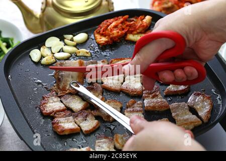 Samgineopsal cotto (grigliata pancia di maiale barbecue), tagliato con forbici, cucina coreana Foto Stock