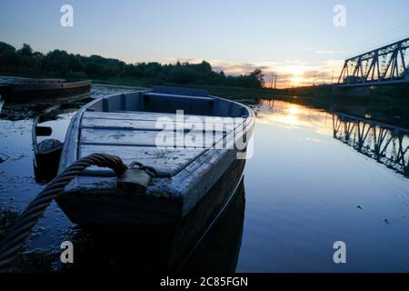 vecchie barche in legno in canoa si ergono sull'acqua durante il tramonto. Il sole soffia sull'acqua blu limpida Foto Stock