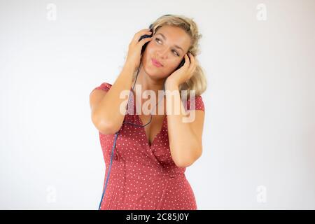 Bella donna bionda sorridente in abito rosso con cuffie Foto Stock