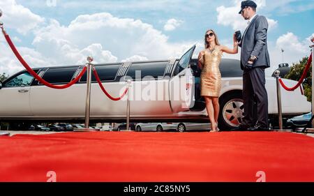 Autista aiutando vip donna o star fuori di limo sul tappeto rosso Foto Stock