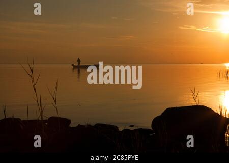 pescatore in barca sul mare dorato del tramonto. tramonto bello e romantico. silhouette di pescatori con la sua barca Foto Stock
