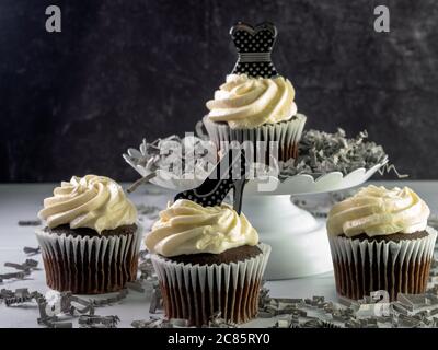 Cupcake al cioccolato con glassa bianca e roteata decorata con un nero Foto Stock