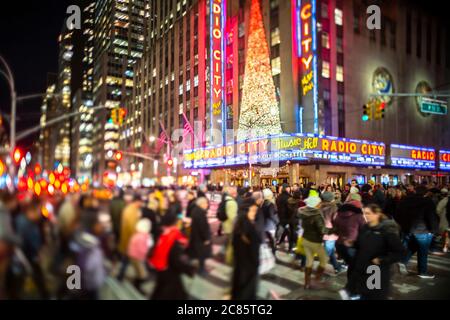 Una folla di persone attraversa la 6th Avenue di fronte al radio City Music Hall Foto Stock