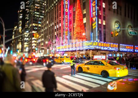 Una folla di persone attraversa la 6th Avenue di fronte al radio City Music Hall Foto Stock