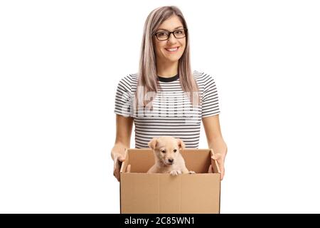 Sorridente giovane donna che porta un cane cucciolo in una scatola isolata su sfondo bianco Foto Stock