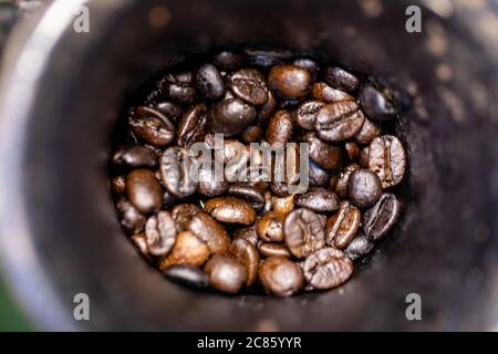 Chicchi di caffè tostati all'interno del macinacaffè manuale. Foto Stock