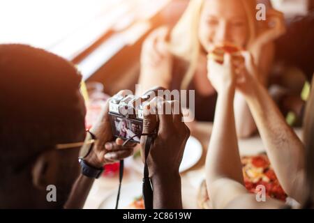 Ragazzi e ragazze attraenti che bevono, mangiano la pizza, sparano tutto il divertimento mentre cenano a casa Foto Stock