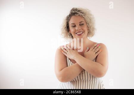 Bionda giovane donna sorridente con le mani incrociate Foto Stock