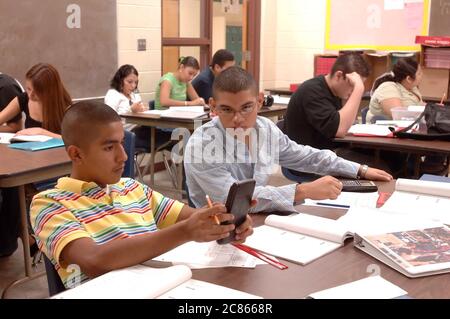 Brownsville, Texas USA, 2 dicembre 2005: Gli studenti della Lopez High School lavorano sui problemi di matematica nella classe Algebra II utilizzando calcolatrici scientifiche portatili. La popolazione studentesca di Lopez HS è ispanica di oltre il 99%. ©Bob Daemmrich Foto Stock