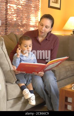 Austin, Texas USA, gennaio 2006: La madre ispanica nei primi anni '30 legge il libro a suo figlio di 22 mesi a casa. Modello rilasciato OK. ©Bob Daemmrich Foto Stock