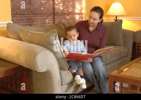 Austin, Texas USA, gennaio 2006: La madre ispanica nei primi anni '30 legge il libro a suo figlio di 22 mesi a casa. Modello rilasciato OK. ©Bob Daemmrich Foto Stock