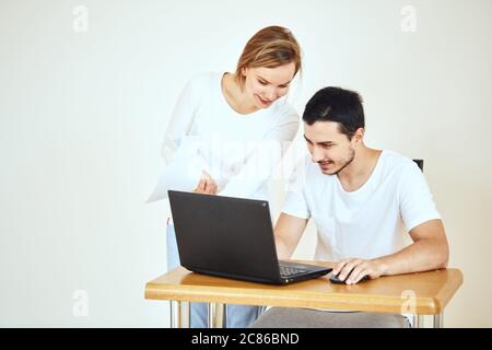 Felice giovane coppia che calcola le fatture con il laptop insieme a casa Foto Stock