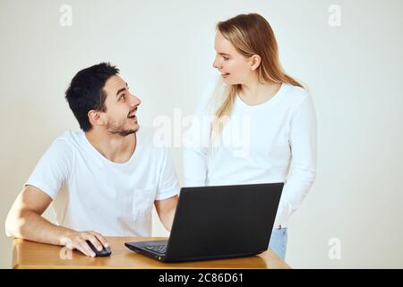 Una coppia giovane scioccante che legge le bollette insieme seduta scrivania a casa Foto Stock