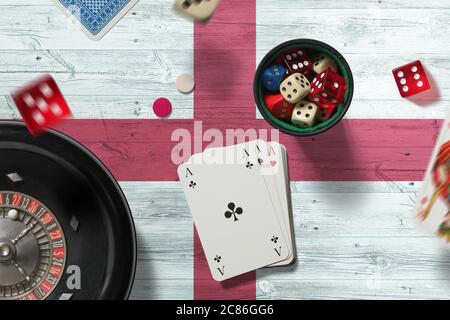 Tema del casinò inglese. Assi nel gioco del poker, carte e chip sul tavolo rosso con sfondo bandiera nazionale. Gioco d'azzardo e scommesse. Foto Stock