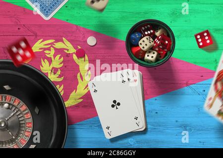 Tema del casinò Eritrea. Assi nel gioco del poker, carte e chip sul tavolo rosso con sfondo bandiera nazionale. Gioco d'azzardo e scommesse. Foto Stock