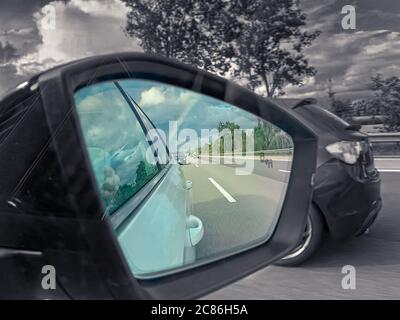 vista dello specchietto retrovisore su un arcobaleno colorato mentre  l'ambiente circostante è bianco e nero, tipo di colore Foto stock - Alamy