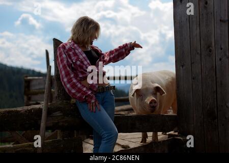 ragazza sul ranch con un maiale Foto Stock