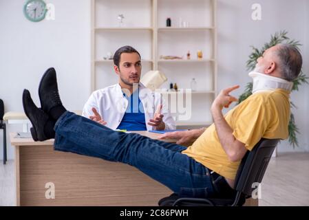 Vecchio collo ferito uomo in visita giovane medico Foto Stock