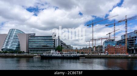 Gru di costruzione che torreggiano sopra i lavori di sviluppo sul North Wall Quay del fiume Liffey con il Centro Congressi sulla sinistra. Foto Stock