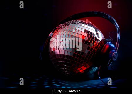 Musica da night club e vita notturna con una copertura da disco a sfera nello specchio che indossa cuffie che riflettono la luce rossa e blu in un club scuro con copia Foto Stock