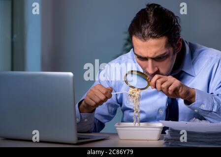 Dipendente affamato che lavora tardi in ufficio Foto Stock