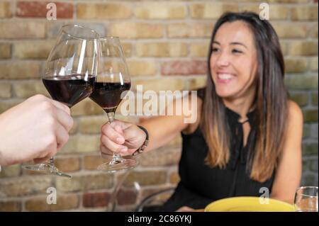 Primo piano di una giovane coppia con un bicchiere di vino rosso al ristorante. Foto di alta qualità Foto Stock