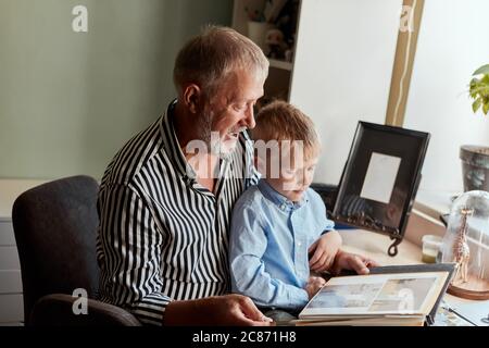 Nonno seduto in poltrona tenendo un neonato Foto stock - Alamy