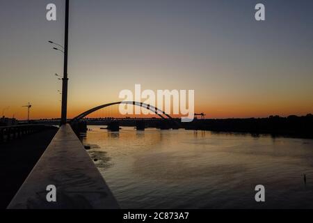 Vista al tramonto del nuovo ponte ad arco sul fiume Dnipro (Dnieper), Kiev, Ucraina. Grande infrastruttura sull'acqua Foto Stock