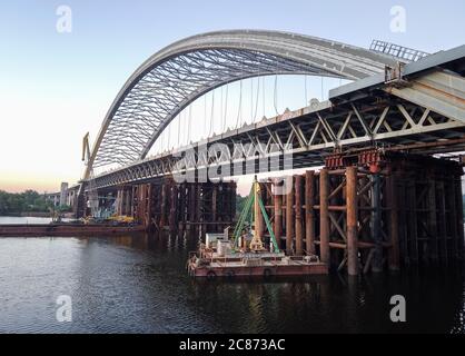 Costruzione enorme di un nuovo ponte ad arco attraverso il fiume Dnipro (Dnieper), Kiev, Ucraina. Grande infrastruttura sull'acqua Foto Stock