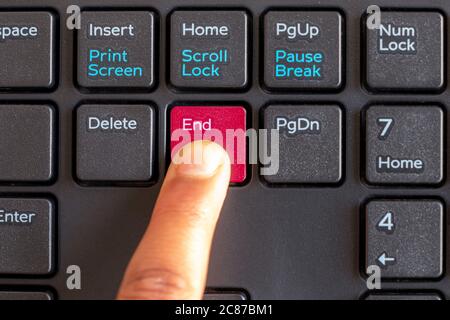Evidenziare il tasto di fine con colore rosso, con il dito che preme il pulsante sulla tastiera isolato su sfondo bianco Foto Stock