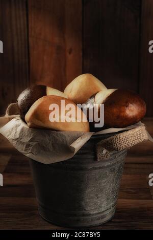 Primo piano di un secchio riempito con panini da cena con luce laterale calda. Formato verticale con spazio di copia. Foto Stock