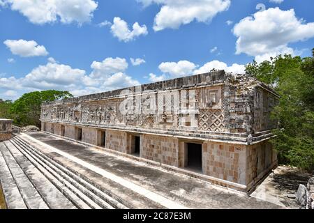 Uno dei quattro palazzi del quadrilatero Nunnery a Uxmal, Messico. Le scale conducono al palazzo, coperto di sculture in pietra ornate. Foto Stock