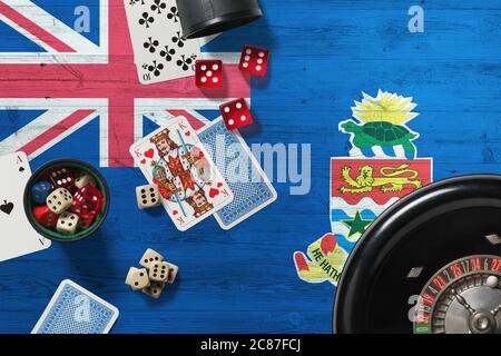 Tema del casinò delle Isole Cayman. Assi nel gioco del poker, carte e chip sul tavolo rosso con bandiera nazionale di legno sfondo. Gioco d'azzardo e scommesse. Foto Stock