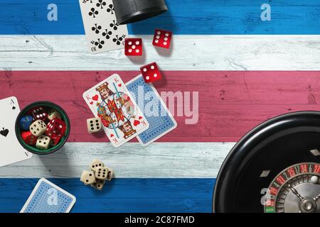 Tema del casinò Costa Rica. Assi nel gioco del poker, carte e chip sul tavolo rosso con bandiera nazionale di legno sfondo. Gioco d'azzardo e scommesse. Foto Stock