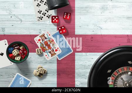 Tema del casinò inglese. Assi nel gioco del poker, carte e chip sul tavolo rosso con bandiera nazionale di legno sfondo. Gioco d'azzardo e scommesse. Foto Stock