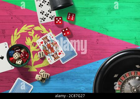 Tema del casinò Eritrea. Assi nel gioco del poker, carte e chip sul tavolo rosso con bandiera nazionale di legno sfondo. Gioco d'azzardo e scommesse. Foto Stock