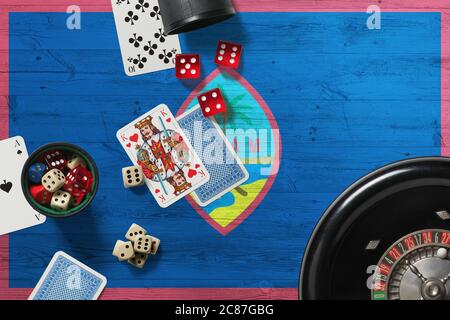 Tema del casinò Guam. Assi nel gioco del poker, carte e chip sul tavolo rosso con bandiera nazionale di legno sfondo. Gioco d'azzardo e scommesse. Foto Stock